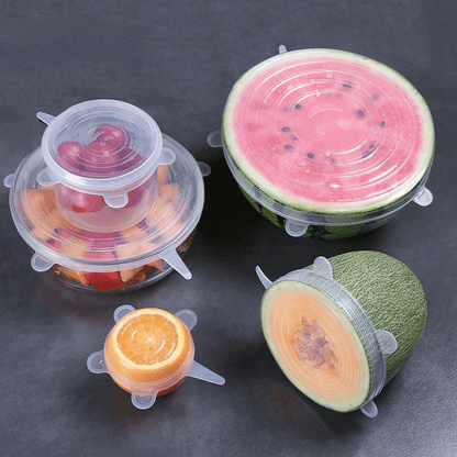Set of silicone food storage covers on fruits and vegetables for effective food preservation.