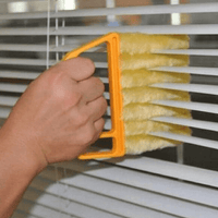Person using a washable window cleaning brush to clean blinds efficiently.
