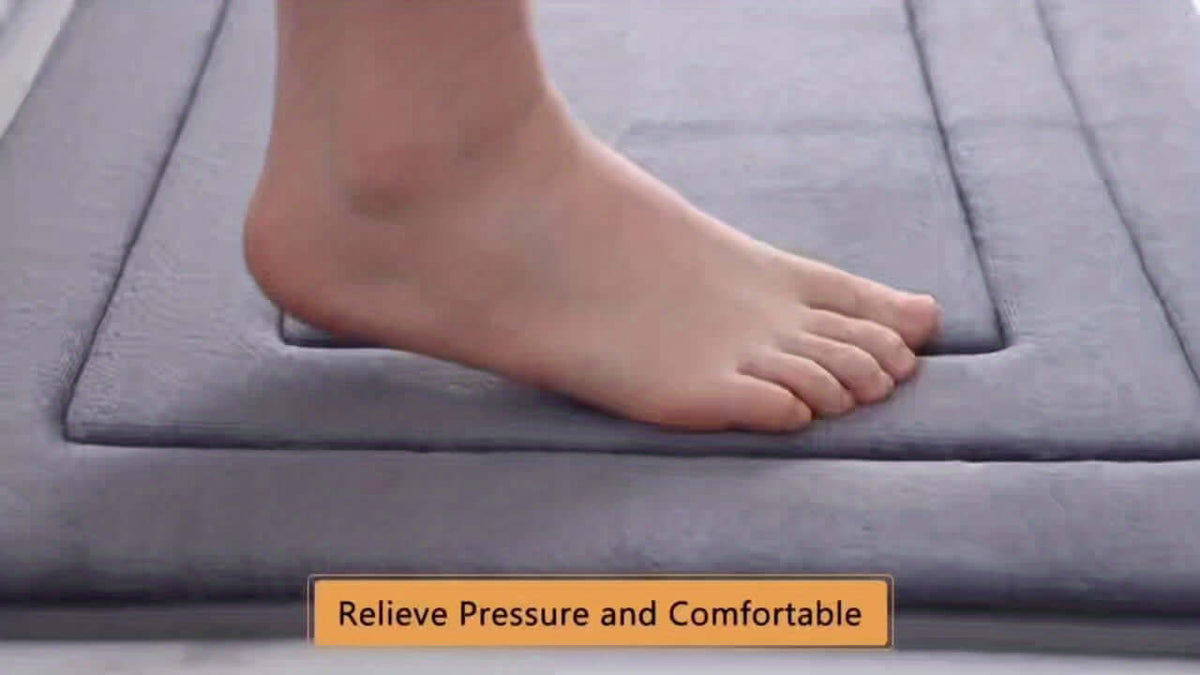 Person's foot stepping on a memory foam bath mat set, showcasing its comfort and pressure-relieving qualities.