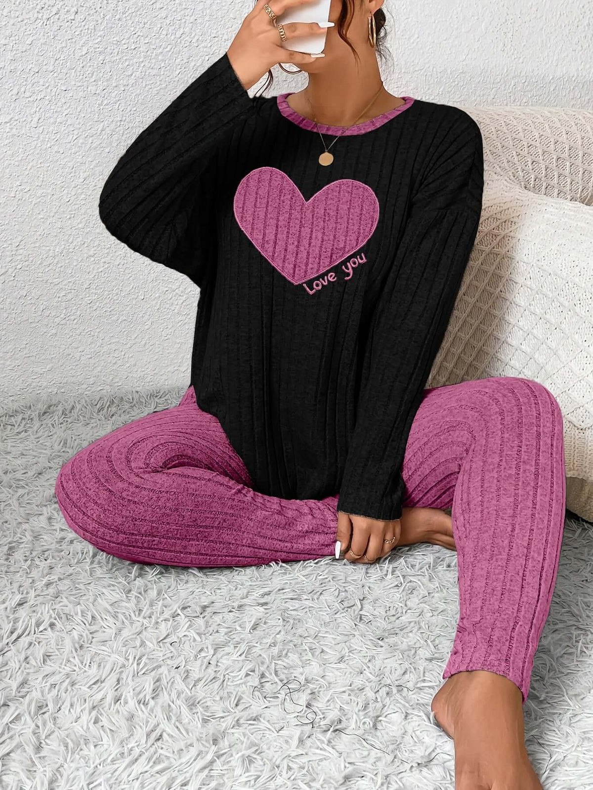Woman sitting in cozy plus size heart fitted loungewear, featuring a pink heart design and comfy textured fabric.