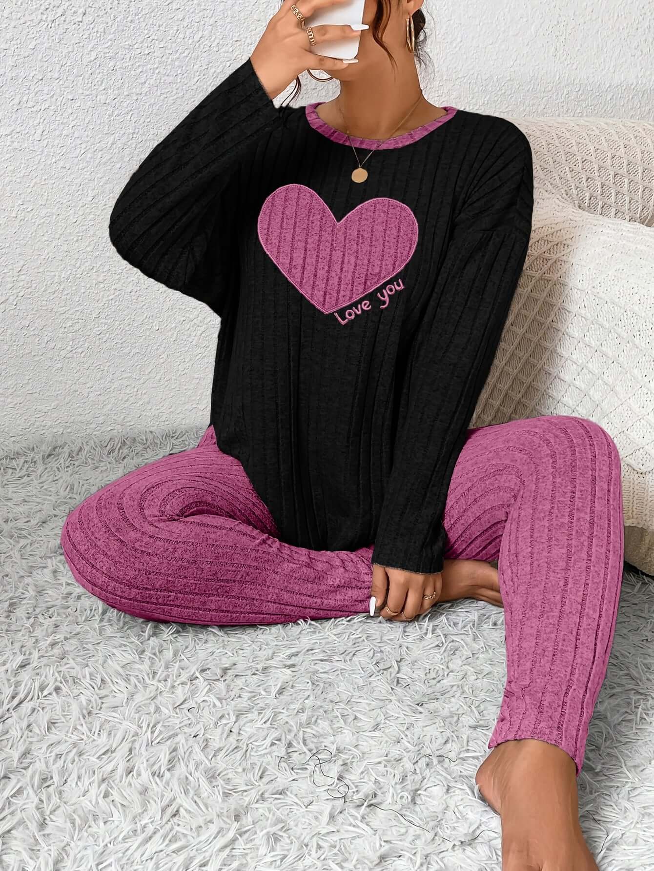 Woman sitting in cozy plus size heart fitted loungewear, featuring a pink heart design and comfy textured fabric.