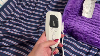 extra large electric heating pad remote control with heat and timer settings on a striped bedspread