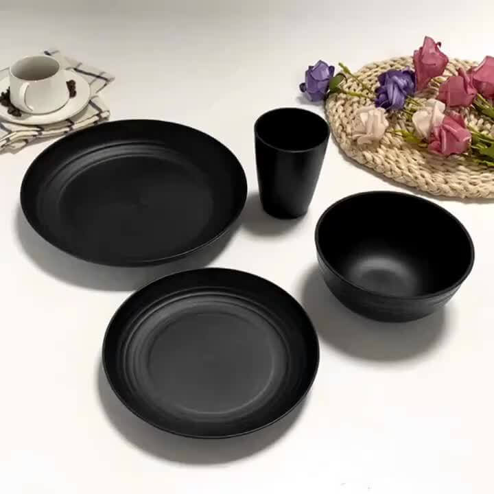 Wheat straw dinnerware set featuring lightweight black plates, bowls, and cups on a decorative table setting.