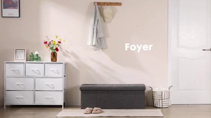 storage ottoman bench placed in a stylish foyer with decorative flowers and a white dresser.