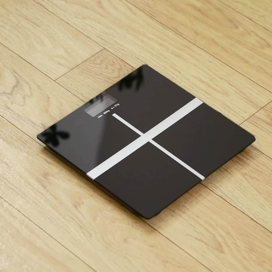 high-precision digital bathroom scale on wooden floor with a sleek black design.