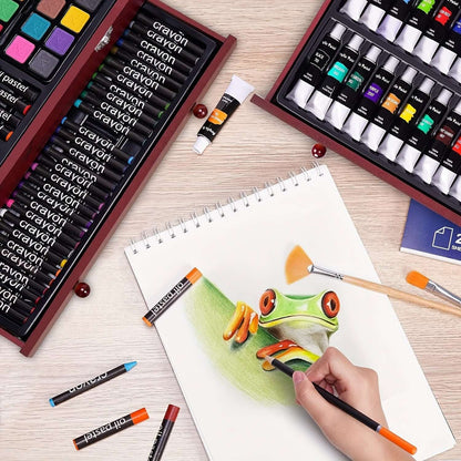 A workspace with PASAMIC non-toxic art supplies showing a hand drawing a colorful frog on sketch paper.