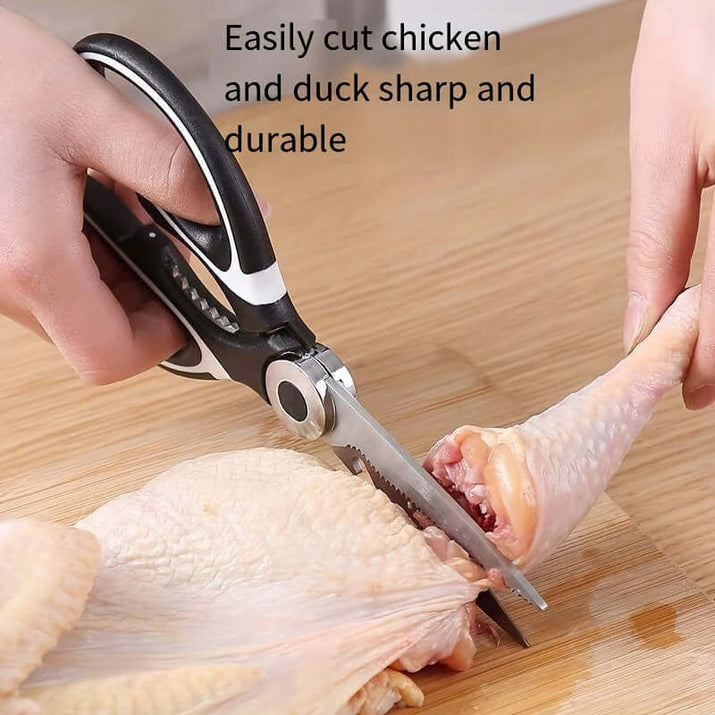Durable stainless steel kitchen shears cutting chicken on wooden board.