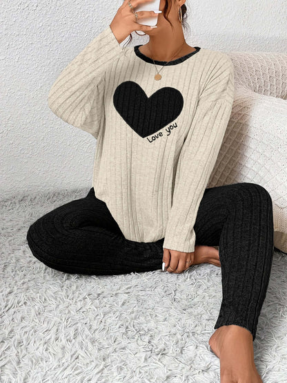 Woman in plus size heart fitted loungewear, featuring a black heart and text that says 'Love you', sitting on a cozy rug.