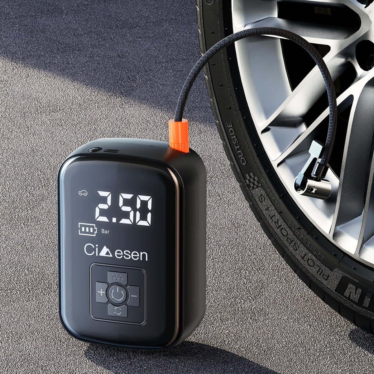 Portable tire inflator with digital display resting on the ground next to a car wheel for easy access.