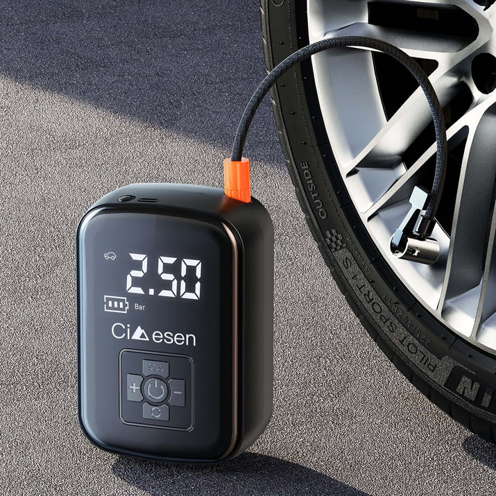 Portable tire inflator with digital display resting on the ground next to a car wheel for easy access.