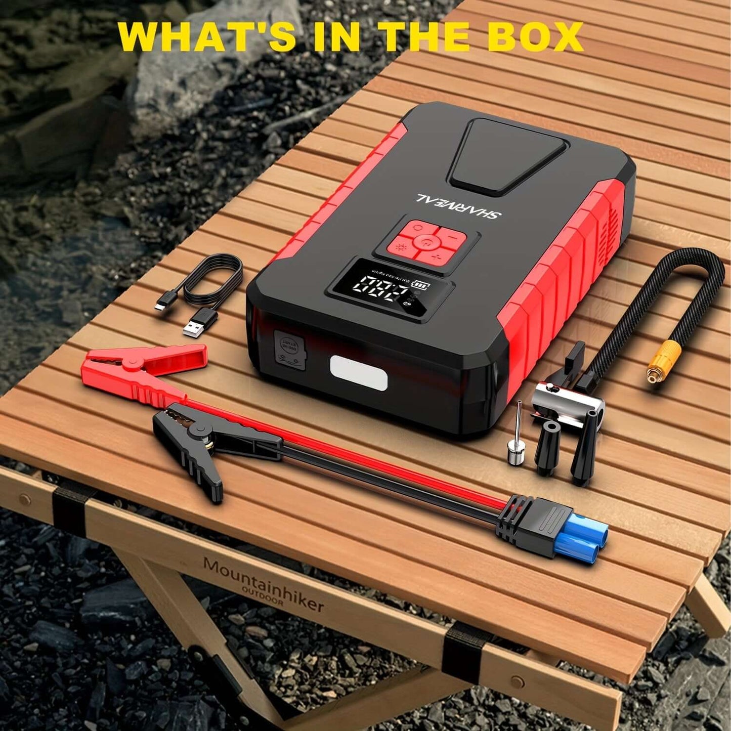 Portable car jump starter and accessories displayed on a wooden table, showcasing what's in the box.