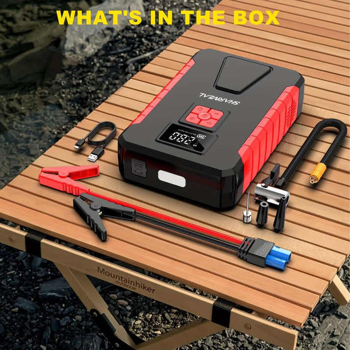 Portable car jump starter and accessories displayed on a wooden table, showcasing what's in the box.
