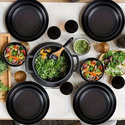 wheat straw dinnerware set featuring black plates, bowls, and serving dishes on a marble table with fresh salads.