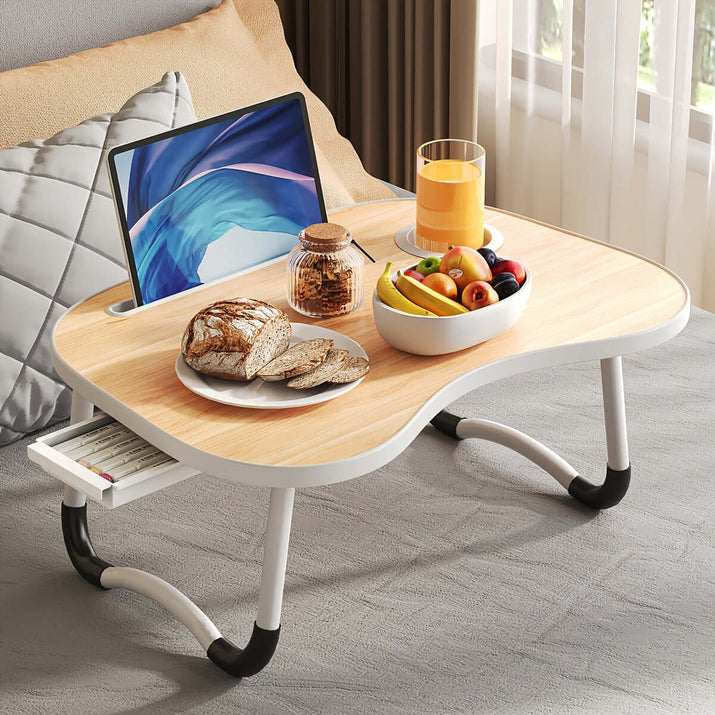 portable laptop bed table with a laptop, breakfast, and a fruit bowl on a cozy bed