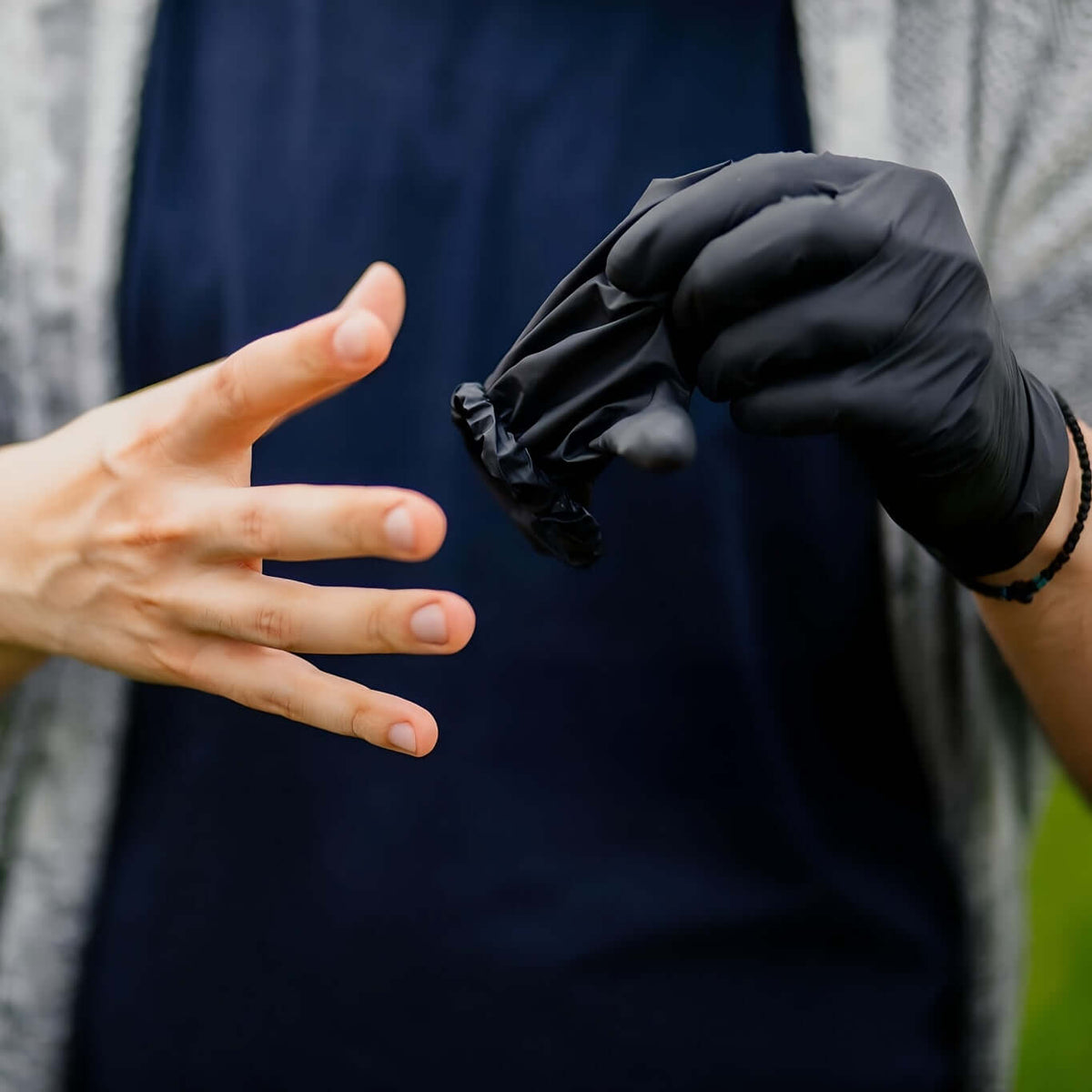 Person wearing disposable nitrile gloves for safety, preparing to use them for protection.
