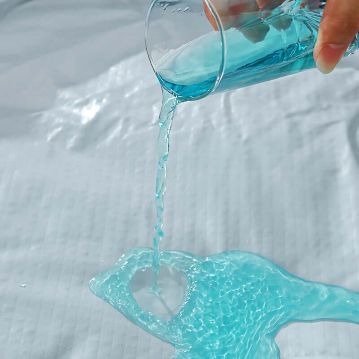 Pouring blue liquid onto ultrasonic embossed polyester fabric specifications demonstrating water resistance.