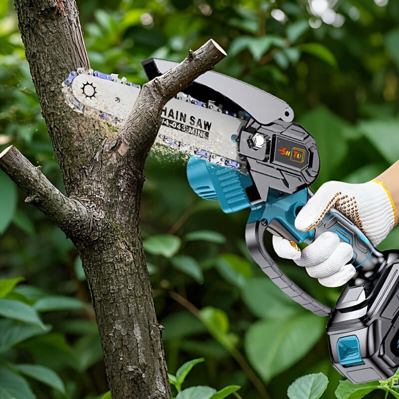 A person using a cordless mini chainsaw to cut a tree branch in an outdoor setting.