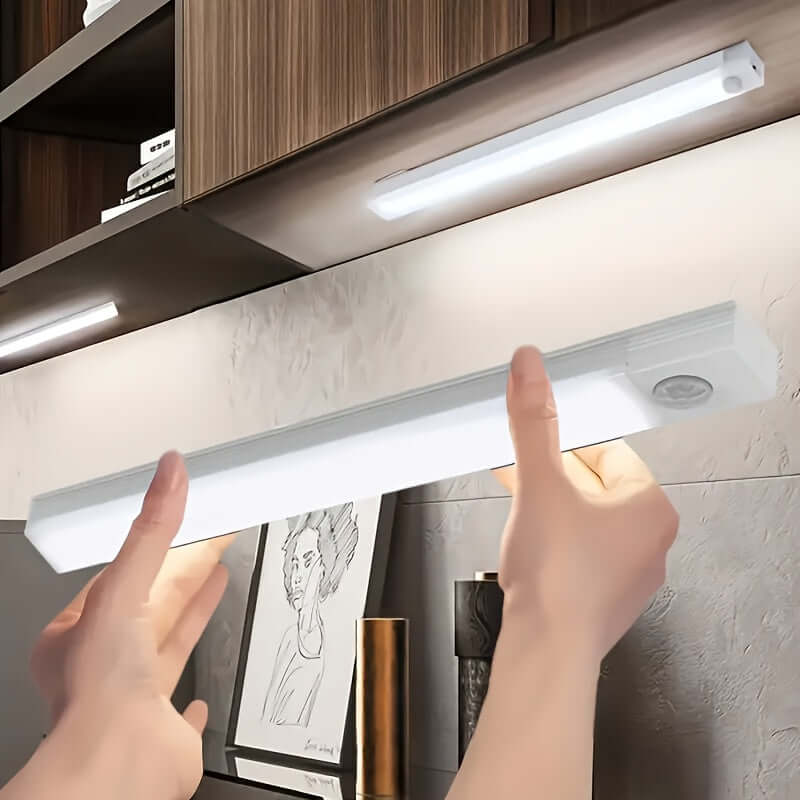 wireless LED under cabinet light being installed with hands reaching for it