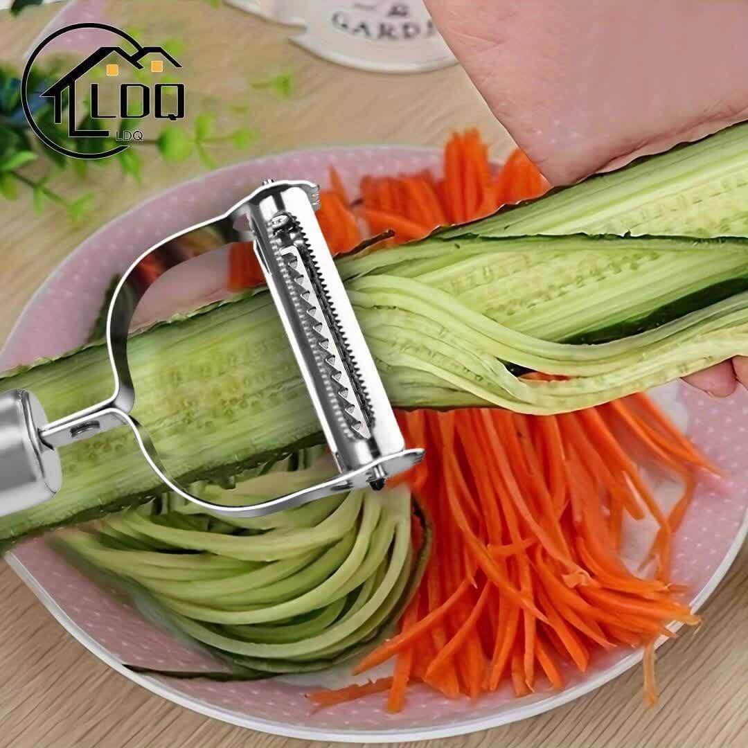 A hand using a stainless steel restaurant cookware peeler on cucumber, with carrot strips in the background.