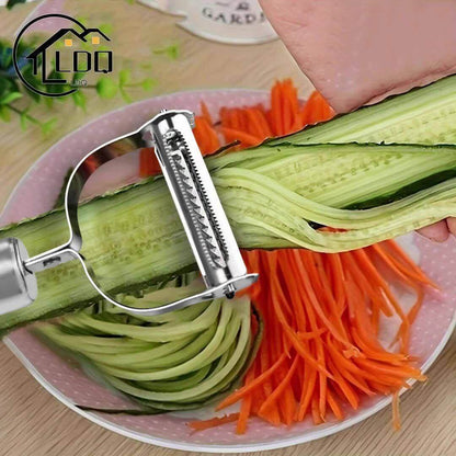 A hand using a stainless steel restaurant cookware peeler on cucumber, with carrot strips in the background.