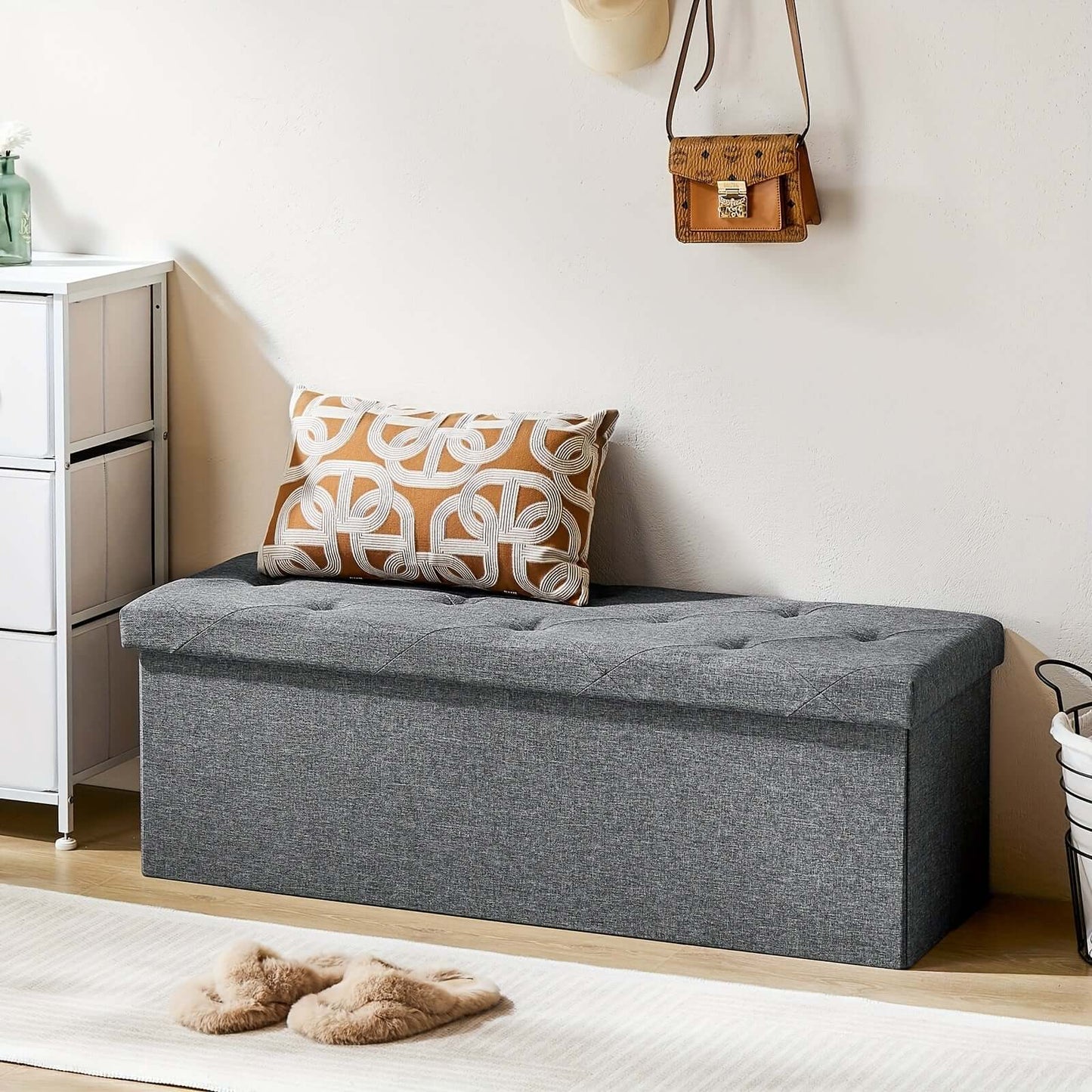 Stylish storage ottoman bench with tufted top and decorative pillow in modern interior setting.
