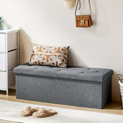 Stylish storage ottoman bench with tufted top and decorative pillow in modern interior setting.