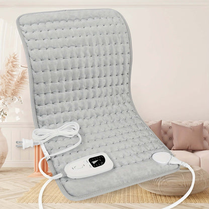 extra large electric heating pad on a beige couch with a controller and power cord visible