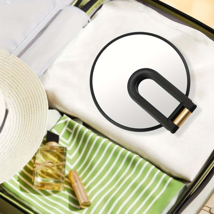 50x magnifying handheld mirror placed inside a suitcase with travel essentials.
