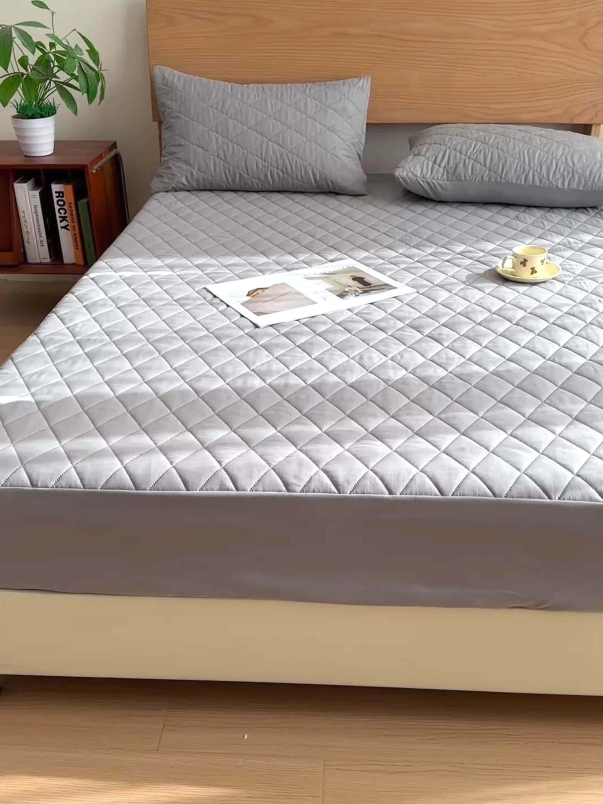 Gray ultrasonic embossed polyester fabric specifications mattress cover on a bed with pillows and a book.
