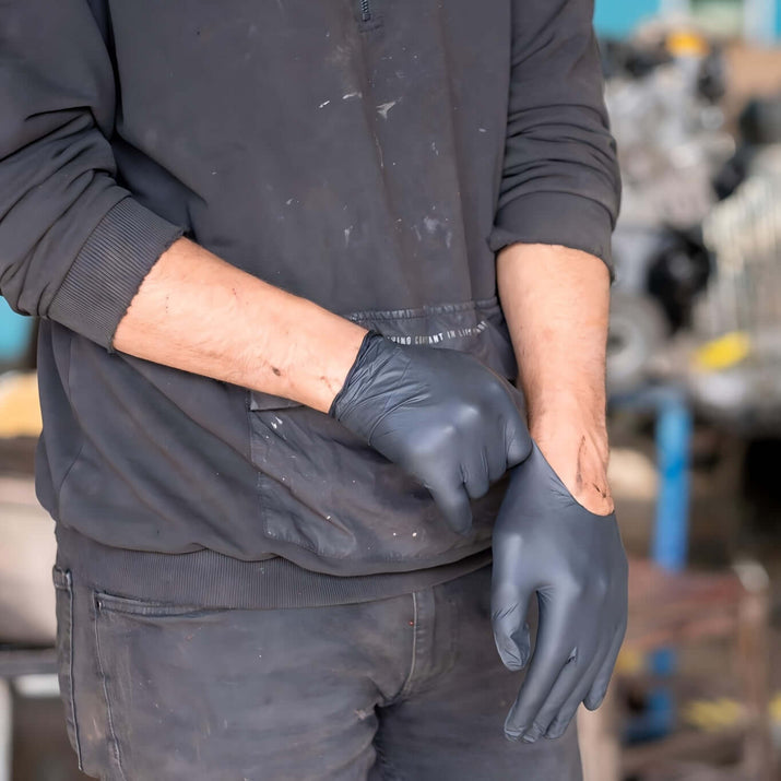 Person wearing disposable nitrile gloves for safety while working in a garage.